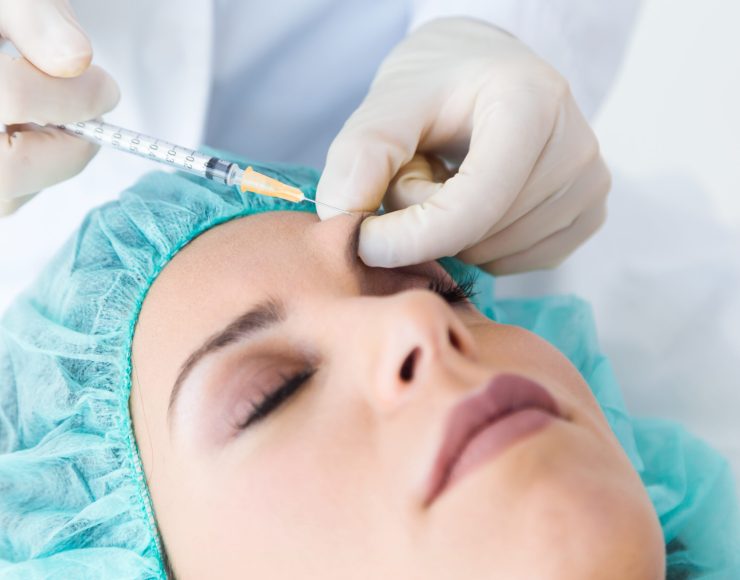 Portrait of beautiful young woman getting botox cosmetic injection in her face.