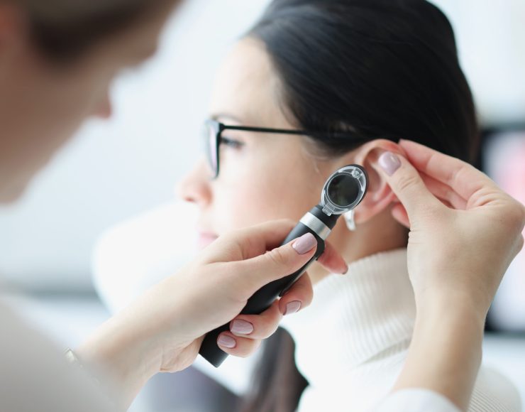 Otorhinolaryngologist examines patient's ear with an otoscope. Otorhinolaryngologist services concept